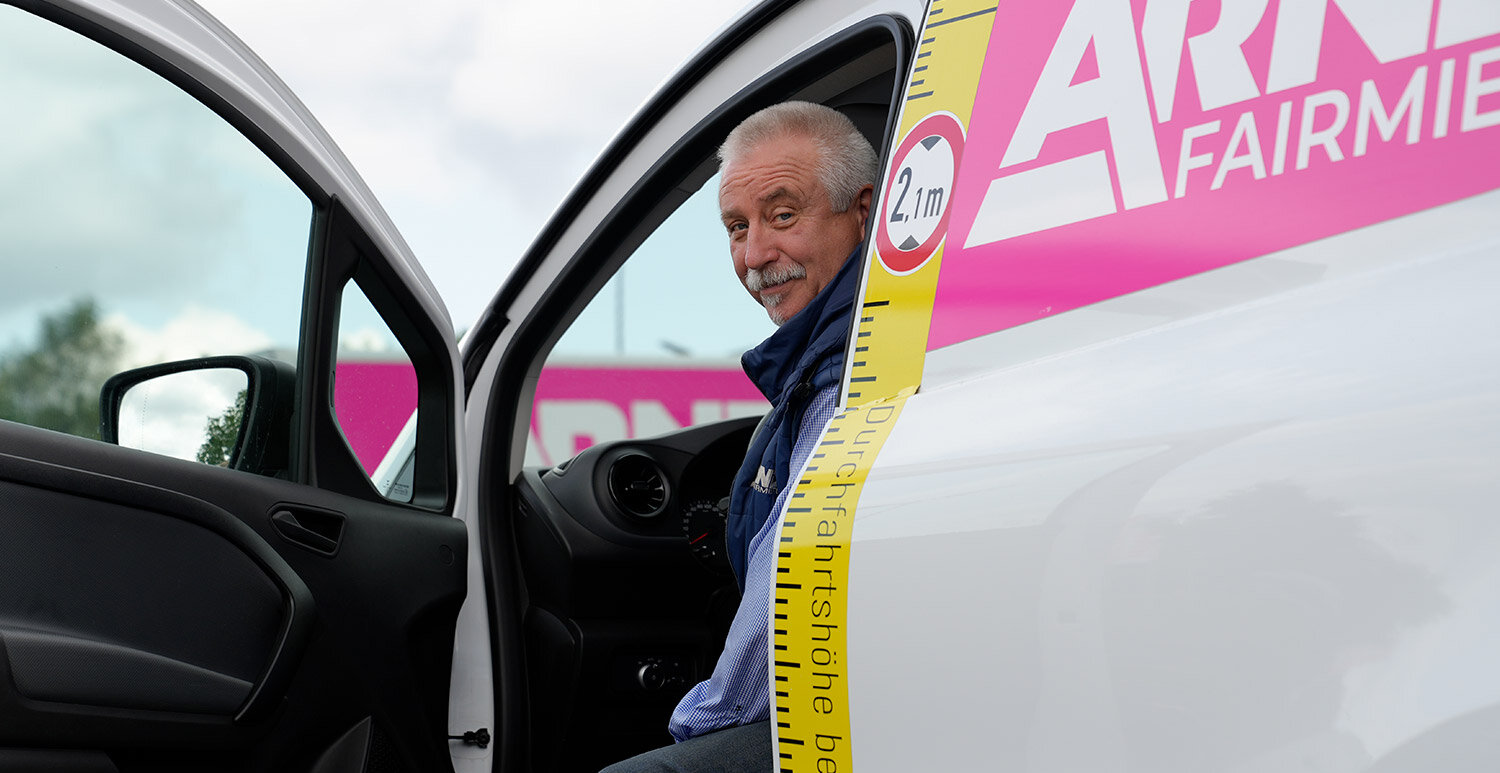 Freundlicher Fahrer in einem Fahrzeug der Arndt Autovermietung: gekennzeichnet mit Durchfahrtshöhe und Firmenbranding | Autovermietung Arndt für Firmenkunden