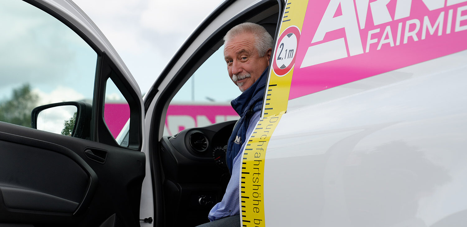 Freundlicher Fahrer in einem Fahrzeug der Arndt Autovermietung: gekennzeichnet mit Durchfahrtshöhe und Firmenbranding | Autovermietung Arndt für Firmenkunden