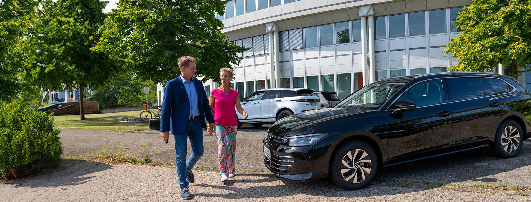 Arndt-Vertriebler und Kundin laufen zufrieden an dem VW Passat vorbei | Autovermietung Arndt für Firmenkunden