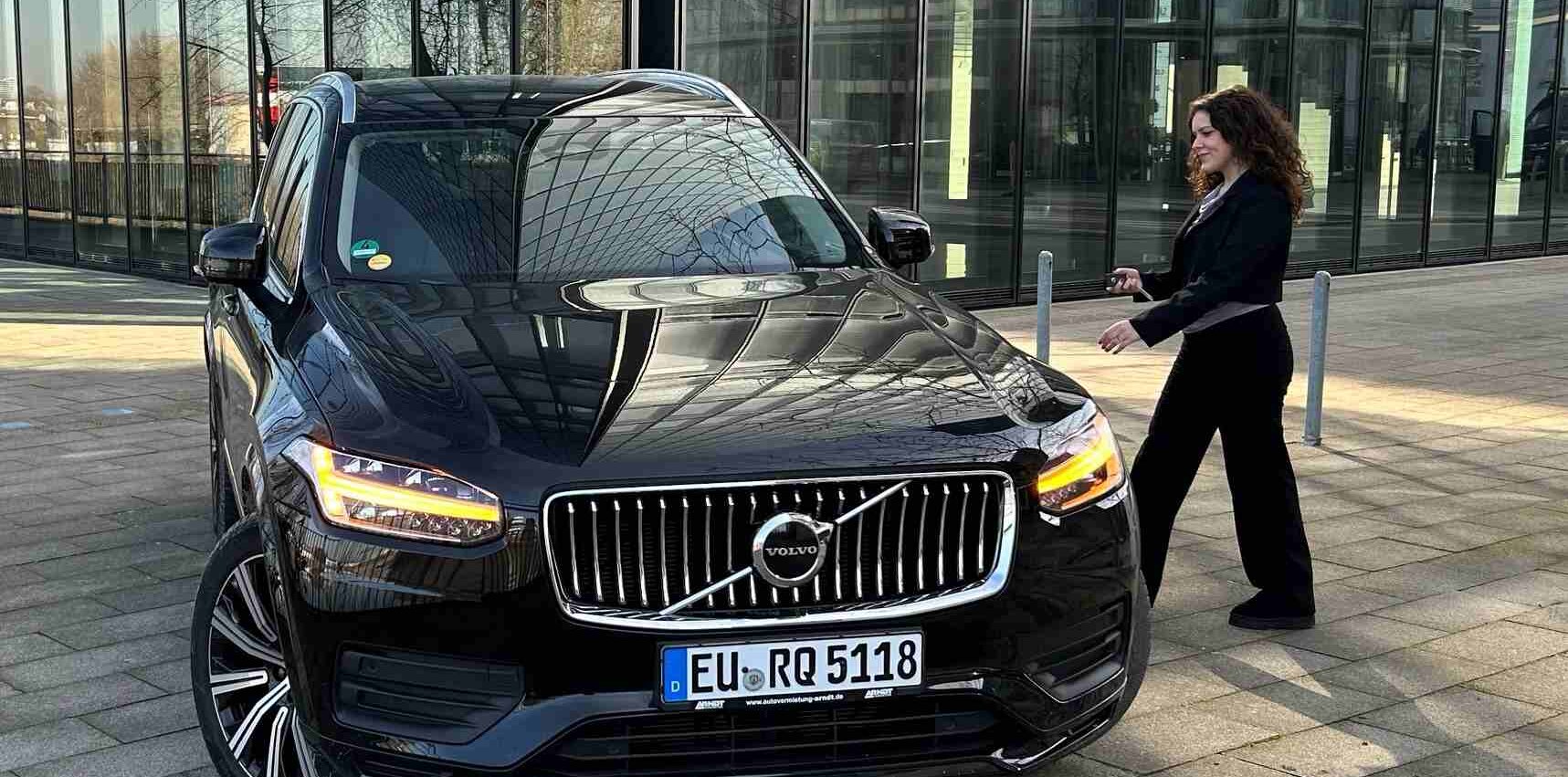 B2B-Kundin läuft zum Mietwagen der Marke Volvo von der Arndt Autovermietung | Autovermietung Arndt für Firmenkunden