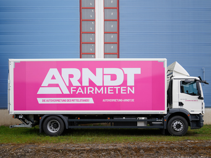 Seitenansicht des MAN 18t auf Wiese und vor Industriegebäude | MAN 18tonner mieten bei Autovermietung Arndt