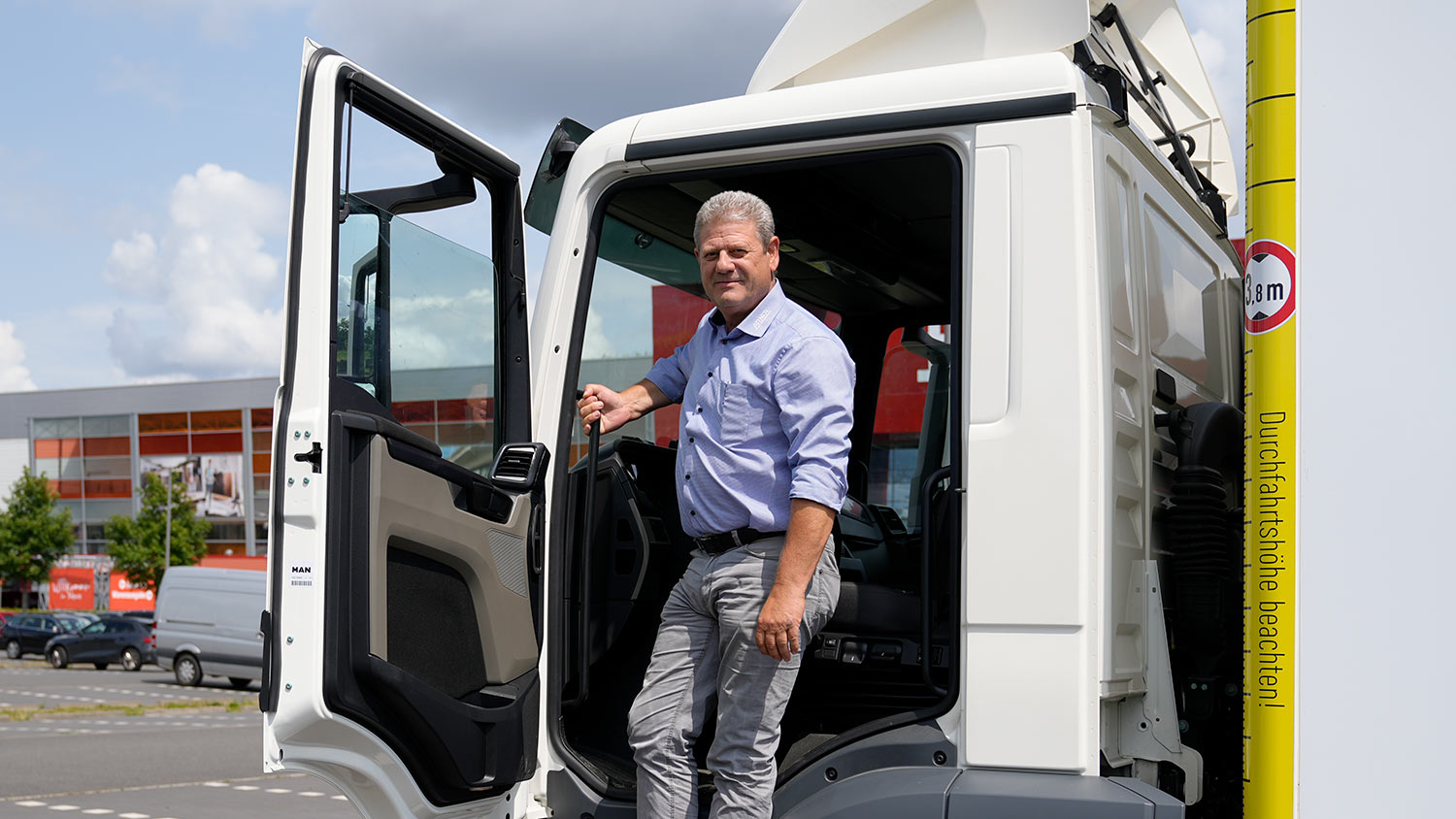 Ein Arndt-Mitarbeiter steigt in den MAN LKW ein, Hinweis am LKW für die maximale Durchfahrtshöhe von 3,8m | Autovermietung Arndt für Firmenkunden